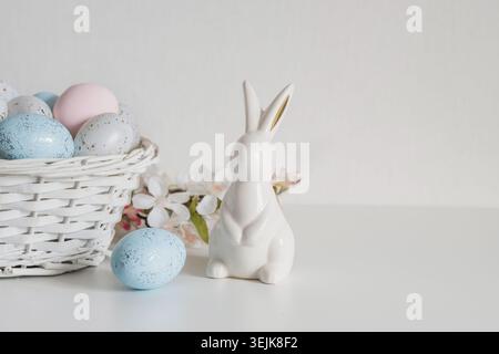 Easter still life with ceramic bunny and pastel eggs on white background Stock Photo