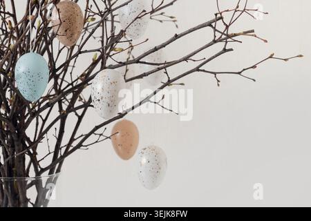 Easter tree decorated white and beige eggs in vase on white . Close up. Stock Photo