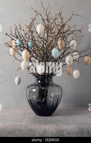 Easter tree decorated white and beige eggs in dark vase on gray background. Stock Photo