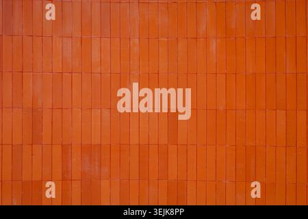 Modern architectural background featuring vertical orange ceramic wall cladding. Stock Photo