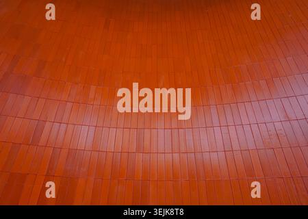 Modern architectural background featuring vertical orange ceramic wall cladding. Stock Photo