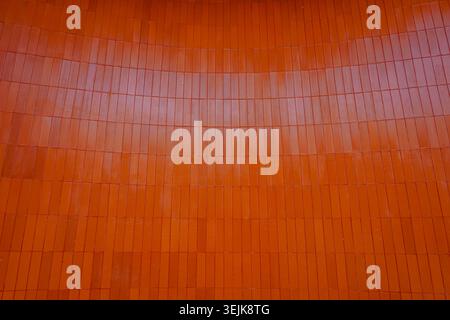 Modern architectural background featuring vertical orange ceramic wall cladding. Stock Photo