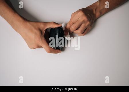 Top view of male hands cleaning modern black vertical mouse with disinfectant wipe, promoting hygiene and preventing spread of germs Stock Photo