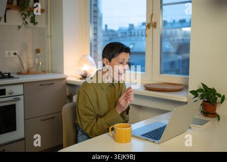 Amazed smiling senior businesswoman looking at laptop screen with surprised smiling expression. Stock Photo