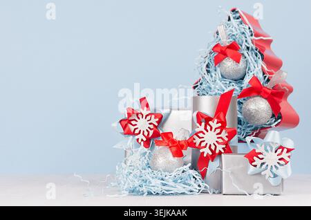 Colorful christmas home decoration -  metallic gift boxes with bright red and blue silk ribbons and christmas tree on white wood Stock Photo