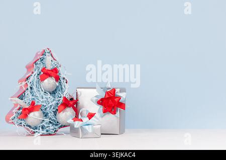 Colorful christmas home decoration -  metallic gift boxes with bright red and blue silk ribbons and christmas tree on white wood Stock Photo