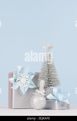 Christmas decoration and gifts in soft blue color - different metallic boxes with ribbons and bows, silver tree, glitter ball on Stock Photo