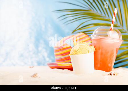 Summer beach vacation - picnic with cold fruit cocktail, ice cream, green apple and sun hat on sunny coast with sand, palm leaf, Stock Photo