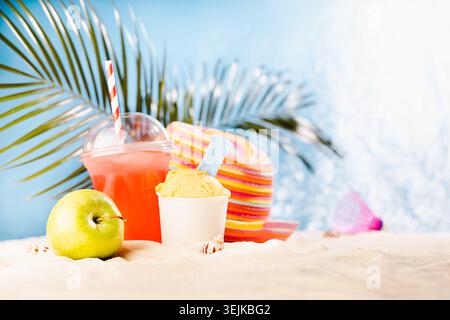 Summer beach vacation - picnic and leisure with cold fruit cocktail, ice cream, green apple, sun hat, beach games on sunny coast Stock Photo