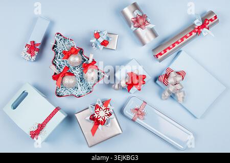 Colorful festive different gift boxes and christmas tree in red, blue and metallic color with silk ribbons and bows on light blu Stock Photo