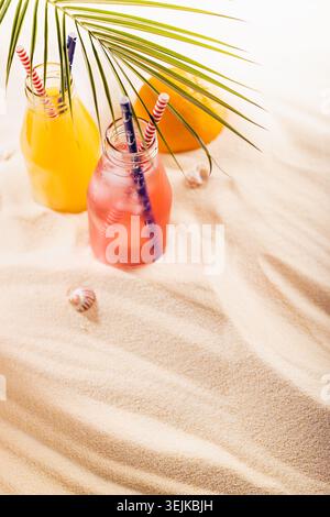 Summertime tropical vacation on sea beach background - picnic with cold fruit yellow and pink cocktail, straw, ice in misted gla Stock Photo