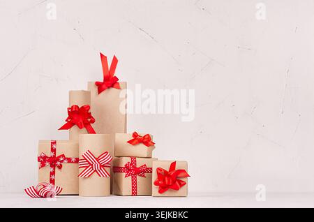 Holiday decoration composition of gift boxes with traditional red ribbons and bows on soft white wood board, copy space. Stock Photo