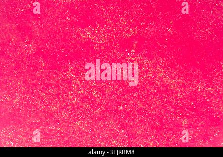 Saturated pink slime with golden glitter particle texture, top view. Stock Photo