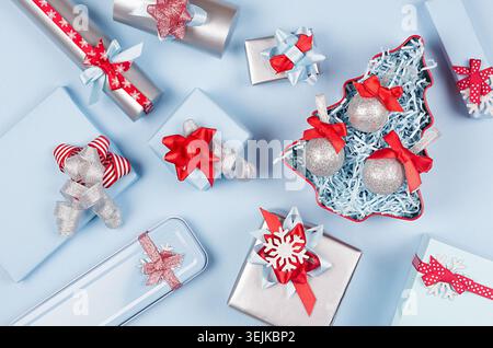 Christmas tree with glitter balls and gift boxes, decorations in pastel blue and silver metallic color with red silk ribbons and Stock Photo