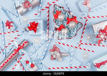 Christmas tree with glitter balls and gift boxes, decorations, straws in pastel blue and silver metallic color with red silk rib Stock Photo