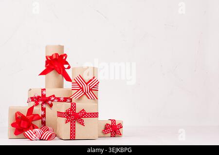 Heap different festive gift boxes with red ribbons and bows on white wood table with copy space. Template for your advertising a Stock Photo