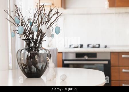Easter decoration with branches and eggs in vase on kitchen table Stock Photo
