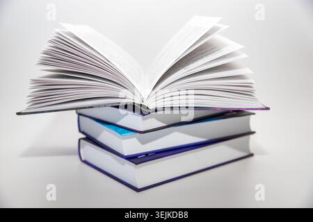 Open hardcover books stacked together on a white background. Education, reading, literature and learning concept. Stock Photo