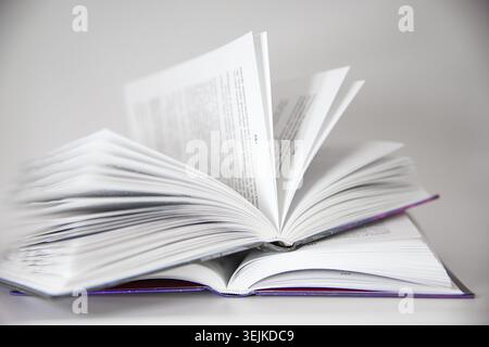 Open hardcover books stacked together on a white background. Education, reading, literature and learning concept. Stock Photo
