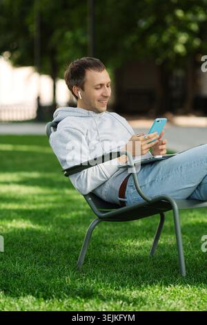 Happy entrepreneur man freelancer work outdoors browse smartphone app talk using wireless headphones Stock Photo