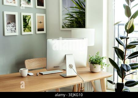Work from home: cozy workplace for freelancer, programmer with computer, keyboard, mouse and plants Stock Photo