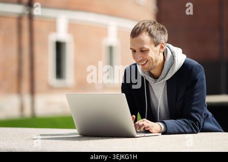Freelancer man check email message in laptop or communicating online outdoor work remotely traveling Stock Photo