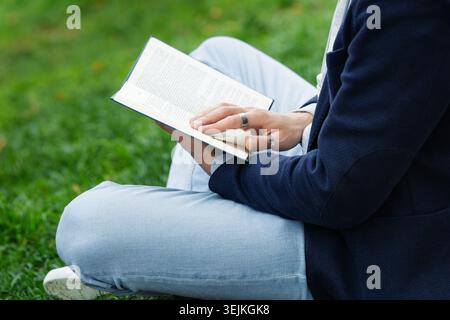 Man reading book in park. Writer, psychologist or student prepare for exam outside on green grass Stock Photo