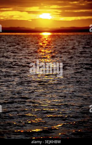 Blurred sunset or sunrise over the ocean with sparkling little waves in sunlight Stock Photo