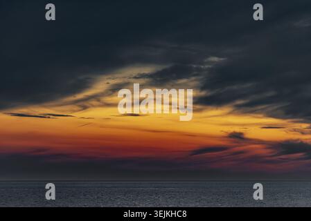 Afterglow of the setting sun seen in a raised cloud cover over the North Sea from Utersum beach on the North Sea island of Foehr Stock Photo