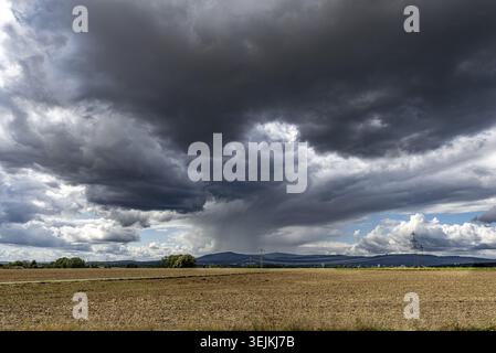 A over the land moving storm with dark gray clouds connected with incoming heavy rain via agricultural area Stock Photo