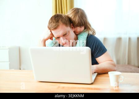Home office. Working from home vs. Dad wearing medical face  Work with  chid kid on the Internet on a laptop at home. quarantine Stock Photo
