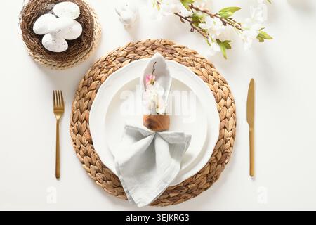 Easter festive table setting with organic brown egg, white bunny and flowers. Stock Photo