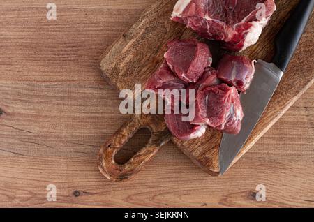 Raw beef meat, sliced on a cutting board, with a knife, no spices, no herbs, top view, wooden table, homemade, no people, Stock Photo
