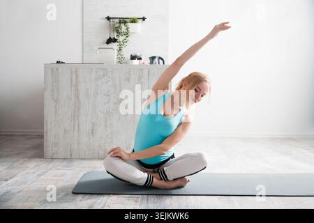 Young pregnant woman doing stretching and yoga in the morning at home. Stock Photo