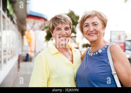 Two senior women or friends walking and talking at summer street. Stock Photo