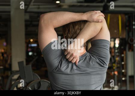 Athlete or caucasian young sporty man doing stretching back and arms. Back View Stock Photo