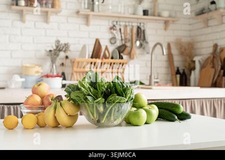 Close up of table with green vegetables and fresh fruit in the kitchen Stock Photo