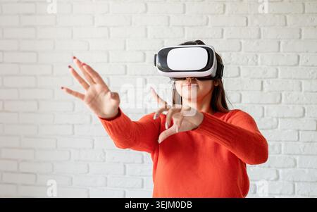 Smile happy woman getting experience using VR-headset glasses of virtual reality at home much gesticulating hands Stock Photo