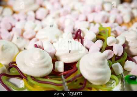 Halloween Ghost Meringue Cookies with Marshmallows and Jelly Worms Candy Background Stock Photo