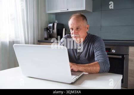 Senior man using laptop at home. Stock Photo