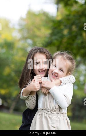Two sisters child girls embrace, playing and having fun together outdoor Stock Photo