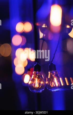 Vintage Edison Light Bulbs with Warm Bokeh on Blue Background Stock Photo