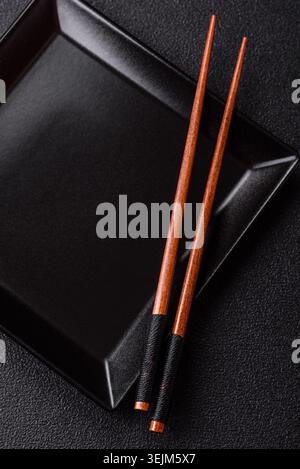 An empty ceramic square black plate with chopsticks for Asian food. An empty square plate Stock Photo
