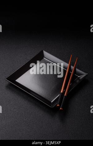 An empty ceramic square black plate with chopsticks for Asian food. An empty square plate Stock Photo