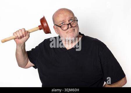 Senior man with glasses holding a plunger looking confused on white background. Stock Photo
