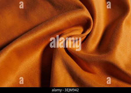 Close-up of Swirled Orange Fabric Texture with Soft Folds Stock Photo