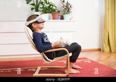 Video Gaming Concept. teenager boy playing with virtual reality goggles, VR headset, modern technology glasses with neon light o Stock Photo