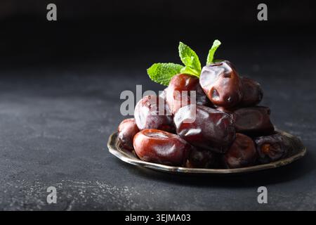 Ramadan kareem. Dates fruits in bowl on black. Close up Stock Photo