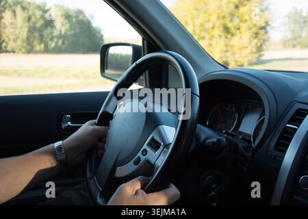 Hands Steering Car on Open Road in Daylight Stock Photo