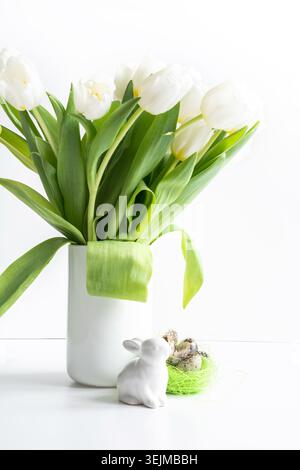 Easter. White tulips in vase, bunny and eggs on white. Stock Photo